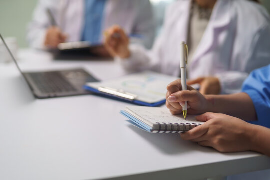 Medical team taking notes during meeting in hospital conference room