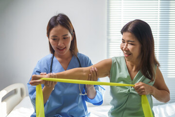 Doctor assisting patient performing exercises with resistance band in hospital room