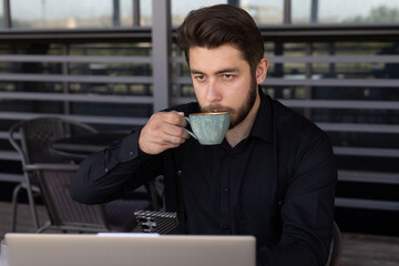 A man using his laptop while sipping coffee