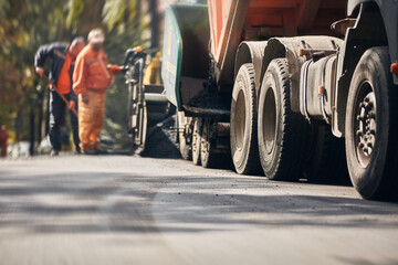 Obraz premium Construction workers working on a new asphalt layer on a public street.