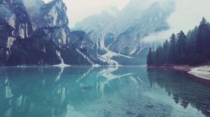 Serene Mountain Lake with Reflection Surrounded by Forest and Misty Peaks in Natural Landscape
