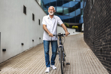 Businessman with bicycle standing in the city. Portrait of a mature man posing with his bicycle.