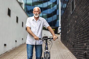 Happy senior man walks his bicycle outdoors and smiles. Cheerful old healthy man enjoy a peaceful walk with bike in a urban scene. Elderly man in casual outfit strolls through the city with bicycle.