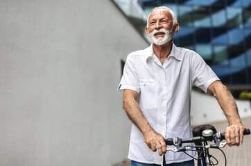 Businessman with bicycle standing in the city. Portrait of a mature man posing with his bicycle.