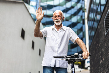 Old man riding a bike and waving his hand. Happy senior man riding a bicycle in nature and waving.