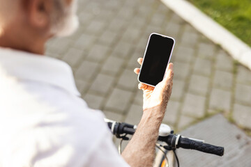 Unrecognisable man with bike using smartphone. Casual handsome senior businessman is going to work by bicycle. He is standing next to bike and using smart phone.