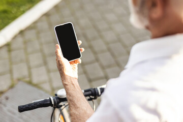 Way to office. Unrecognisable senior businessman texting on phone, walking with bicycle on street. Close up of businessman hand using smartphone on the street.