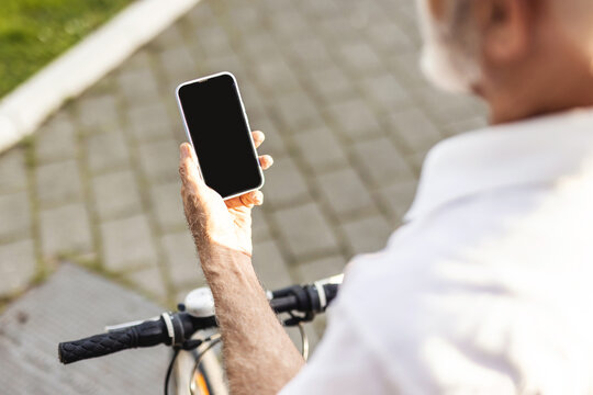 Way to office. Unrecognisable senior businessman texting on phone, walking with bicycle on street. Close up of businessman hand using smartphone on the street.