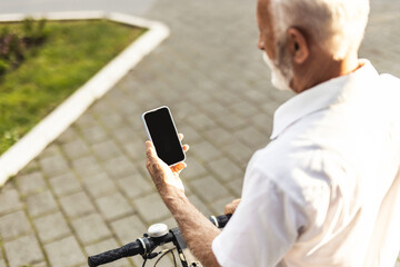 Unrecognisable man with bike using smartphone. Casual handsome senior businessman is going to work by bicycle. He is standing next to bike and using smart phone.