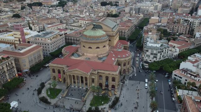 Aerial 4k drone footage of Teatro Massimo in Palermo, Sicily, Italy during a dramatic sunset, showcasing the historic opera house, vibrant city streets, rooftops, and panoramic views