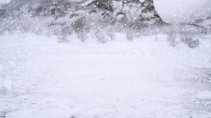 Winter scene with snowfall descending upon a snowy field and covering the ground and trees. Seasonal design or holiday themes for winter