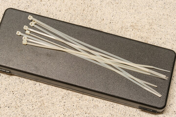 Several zip ties on a black box, lying on a concrete ground. Selective focus.