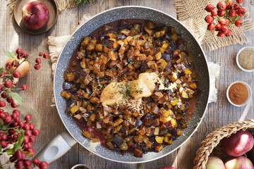 Preparation of homemade chutney or relish from fresh plums, apples, ginger, onion and spices in a pan