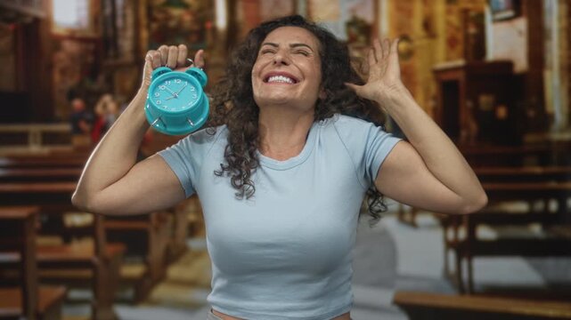 Woman holds turquoise alarm clock to her temple inside church pews beside stone columns near wooden altar; contemplation patience devotion serenity.