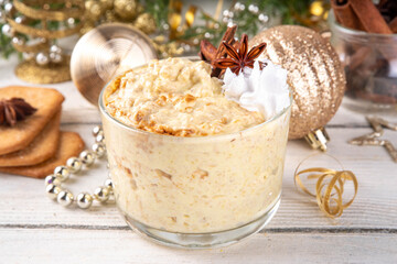 Christmas High-Protein Breakfast Eggnog Overnight Oats with whipped cream and spices, on Xmas decorated background, tasty sweet egg nog oatmeal recipe idea