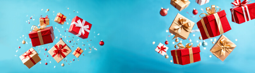 Fototapeta premium christmas gifts and ornaments flying with copy space on blue background