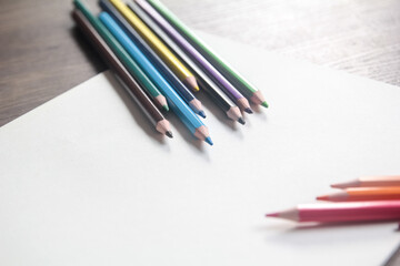 Obraz premium Group of colorful pencils diagonally aligned on a blank white sheet, ready for design or drawing with ample copy space.