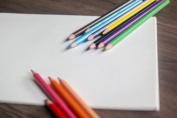 Group of colorful pencils diagonally aligned on a blank white sheet, ready for design or drawing with ample copy space.