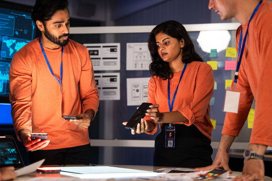 Startup team brainstorming with smartphones and digital tools in a high-tech office, collaborating on UX design, app development, and digital solutions, teamwork, innovation, and corporate planning