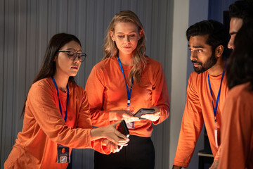 Diverse group of professionals collaborating during a team project. Colleagues gather around, sharing ideas with smartphones and engaging in discussion, workplace culture, digital transformation