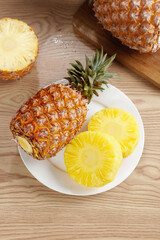 Fresh Golden Pineapple Rings and Half Fruit on White Plate with Wooden Background