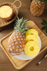 Fresh Pineapple Slices on Wooden Tray with Whole Tropical Fruit in Wicker Basket