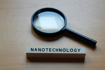 nanotechnology concept. magnifying glass with the word written on a wooden block