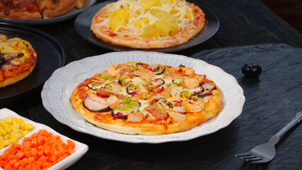 Hot spicy bacon and ham pizza with fresh toppings on white plate with vegetable sides
