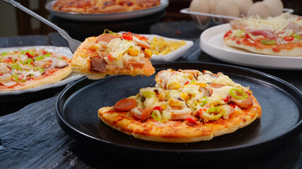 Fresh baked pizza slice with ham bacon cheese toppings served on black plate delicious homemade Italian food