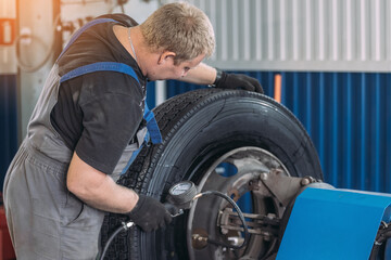A mechanic inspects and measures tire pressure in an auto repair shop. The setting is professional and focused on vehicle maintenance.