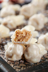 Handmade wontons with meat filling on bamboo steamer - traditional Chinese dumplings freshly wrapped for cooking