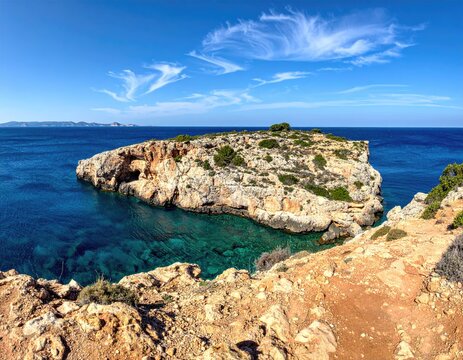 Rocky islet in turquoise water, dramatic cliffs