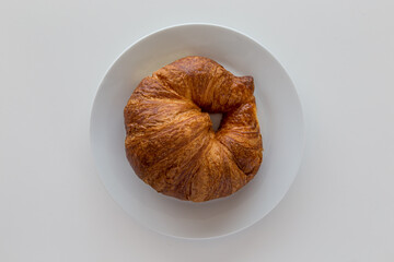 Cornetto dolce su piatto e tavolo bianchi