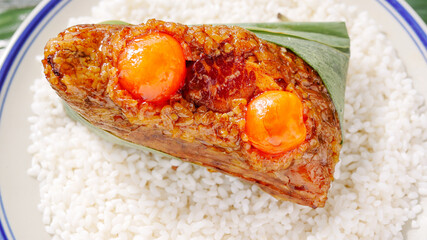 Handmade glutinous rice dumpling with salted egg yolk and meat filling on white rice