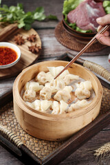 Handmade Fresh Wontons in Bamboo Steamer with Chopsticks and Raw Meat Ingredients for Traditional Asian Cooking