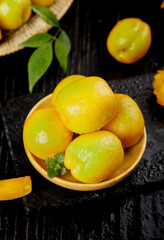 Fresh Ripe Yellow Apricots in Wooden Bowl with Green Leaves on Dark Slate Surface