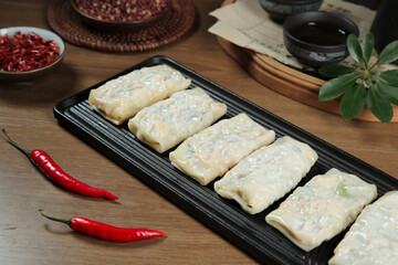 Handmade Asian Spring Rolls with Thin Translucent Crust and Red Chili Peppers on Wooden Table
