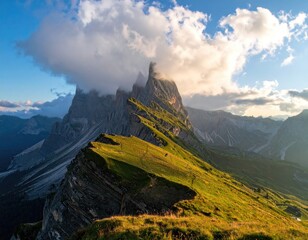 Dramatic mountain peak bathed in golden light, with a grassy ridge leading to it.  Clouds gather at its summit