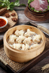 Goldfish shaped wontons in bamboo steamer with ingredients for making small dumplings in clear broth