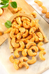 Salted Vietnamese Crispy Cashews in Bamboo Basket on Wooden Board with Fresh Mint Garnish
