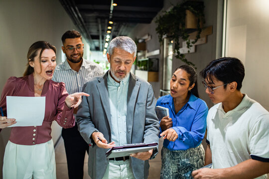 Group of business people talking while walking in a office building hallway