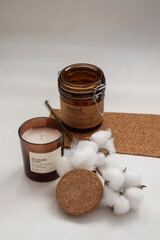 composition on the table. candles in brown jars, a cotton branch and a cork board