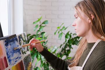 Beautiful female artist painting picture in art studio.