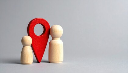 Wooden figurines stand beneath a red map pin on a light gray surface