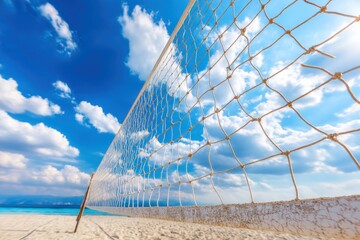 A beach volleyball net stretches across white sand under a bright blue sky with scattered clouds and ocean in the background