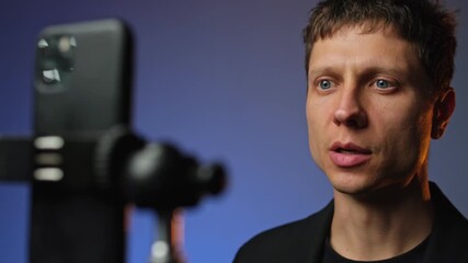 Motivational blogger recording video on smartphone rgb light modern setup young man in suit