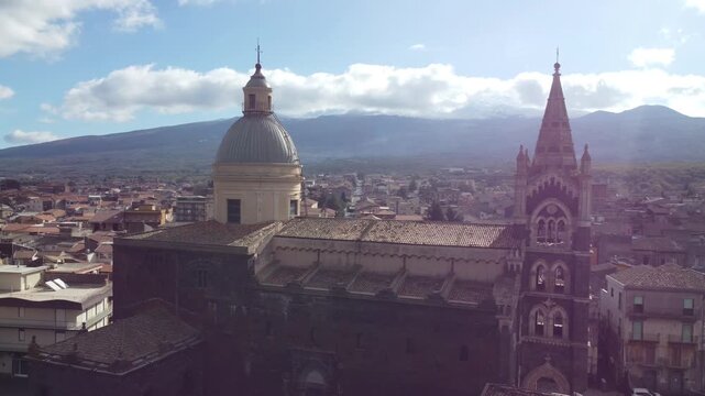 Aerial drone footage of Randazzo in Sicily focusing on the historic center with Basilica di Santa Maria Assunta and the town&rsquo;s medieval architecture, with Mount Etna rising clearly in the background.