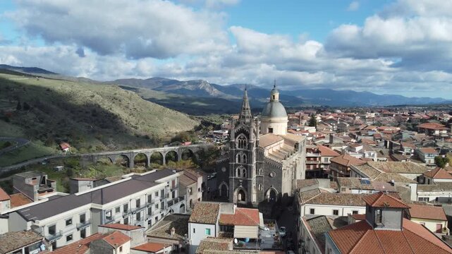 Aerial drone footage of Randazzo in Sicily focusing on the historic center with Basilica di Santa Maria Assunta and the town&rsquo;s medieval architecture, with Mount Etna rising clearly in the background.
