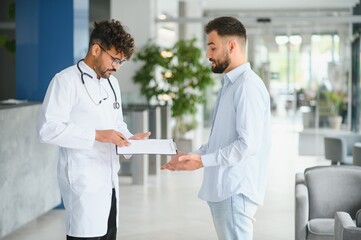 Obraz premium Doctor showing medical record to patient in hospital hall