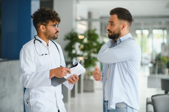 Doctor listening to patient describing symptoms in hospital hall - Powered by Adobe